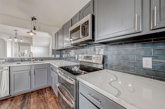 kitchen with stainless steel appliances, pendant lighting, a sink, and gray cabinetry