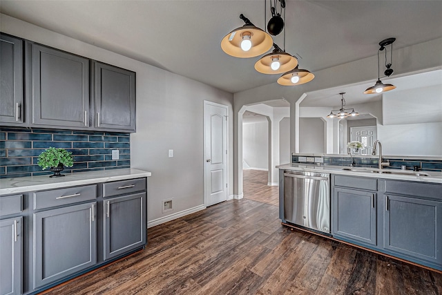 kitchen featuring arched walkways, dishwasher, light countertops, pendant lighting, and a sink