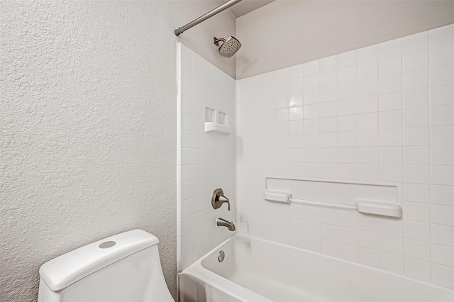 bathroom with a textured wall, shower / bathing tub combination, and toilet