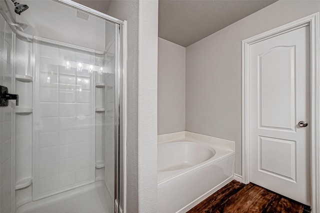 full bath featuring wood finished floors, a stall shower, and a garden tub