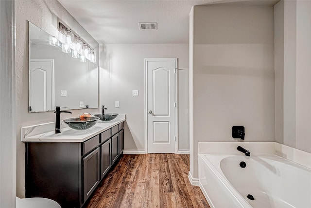 full bath featuring double vanity, wood finished floors, a sink, and visible vents