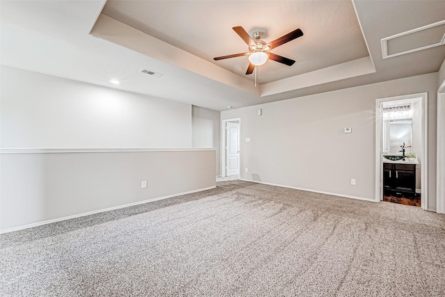 carpeted spare room featuring ceiling fan, a raised ceiling, visible vents, and baseboards