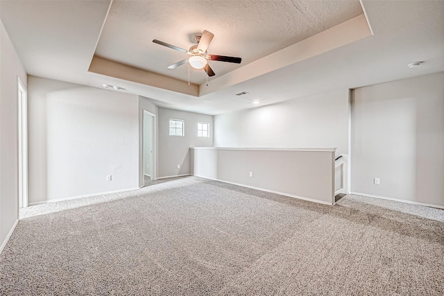 carpeted spare room with ceiling fan, baseboards, a raised ceiling, and a textured ceiling