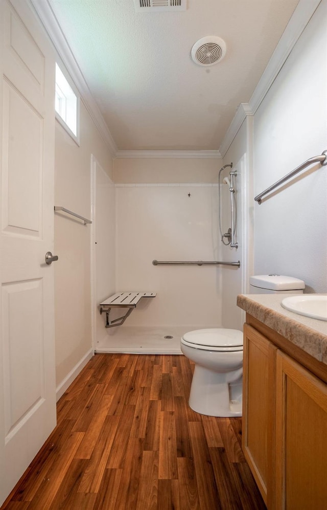 bathroom with vanity, wood-type flooring, ornamental molding, a shower, and toilet