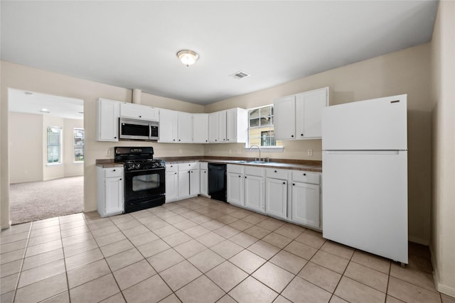 kitchen featuring white cabinetry, sink, light tile patterned floors, and black appliances