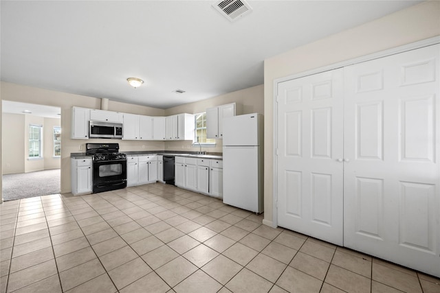 kitchen with white cabinetry, black appliances, a healthy amount of sunlight, and light tile patterned flooring