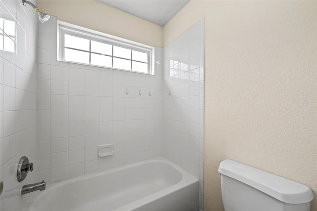 bathroom with tiled shower / bath combo and toilet