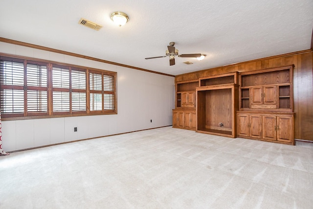 unfurnished living room with crown molding, light colored carpet, ceiling fan, and a textured ceiling