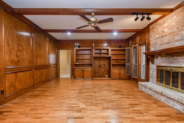 unfurnished living room featuring ceiling fan, light hardwood / wood-style floors, a brick fireplace, beamed ceiling, and wood walls