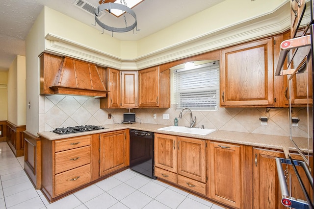 kitchen featuring sink, premium range hood, backsplash, black dishwasher, and stainless steel gas cooktop