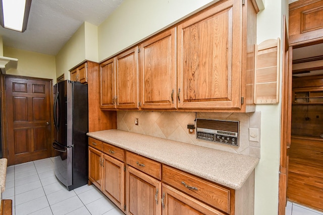 kitchen with decorative backsplash, stainless steel refrigerator, and light tile patterned flooring