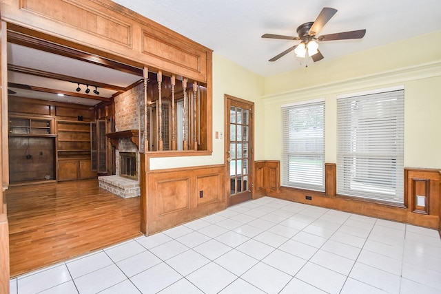 empty room featuring built in shelves, light tile patterned floors, beamed ceiling, ceiling fan, and a fireplace