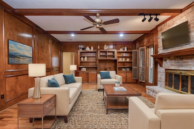 sitting room featuring a brick fireplace, beam ceiling, wooden walls, and light wood-type flooring