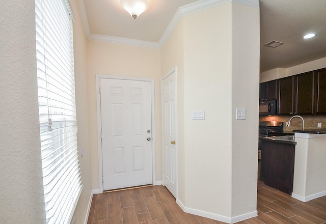 hallway with a healthy amount of sunlight, ornamental molding, and sink