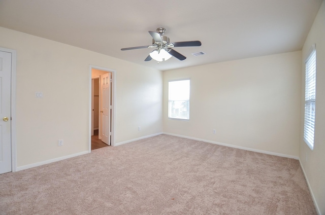 carpeted spare room with a wealth of natural light and ceiling fan