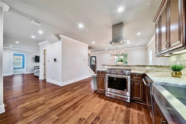 kitchen with dark hardwood / wood-style flooring, stainless steel stove, island exhaust hood, light stone countertops, and decorative backsplash