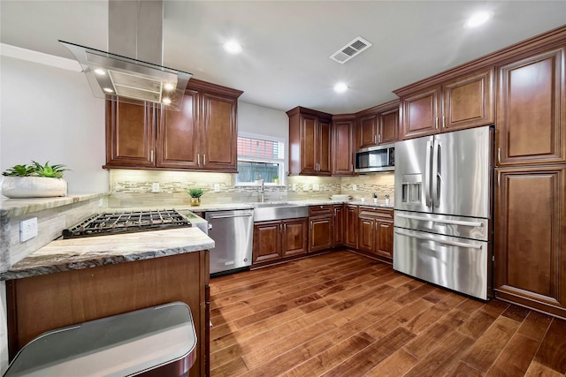 kitchen with sink, dark hardwood / wood-style floors, kitchen peninsula, island exhaust hood, and stainless steel appliances