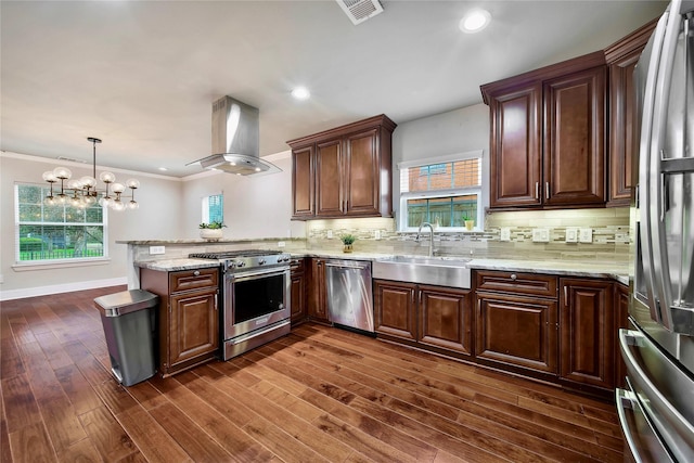 kitchen featuring decorative light fixtures, sink, island exhaust hood, kitchen peninsula, and stainless steel appliances