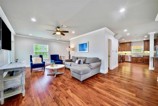 living room with hardwood / wood-style flooring, ornamental molding, sink, and ceiling fan