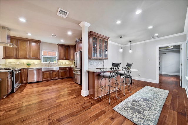 kitchen with a breakfast bar, pendant lighting, sink, light stone counters, and stainless steel appliances