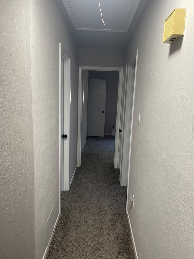 hall with dark colored carpet