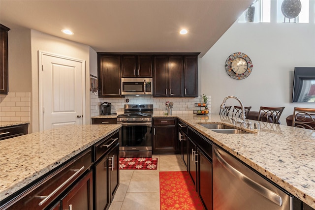 kitchen featuring sink, light tile patterned floors, stainless steel appliances, light stone countertops, and decorative backsplash