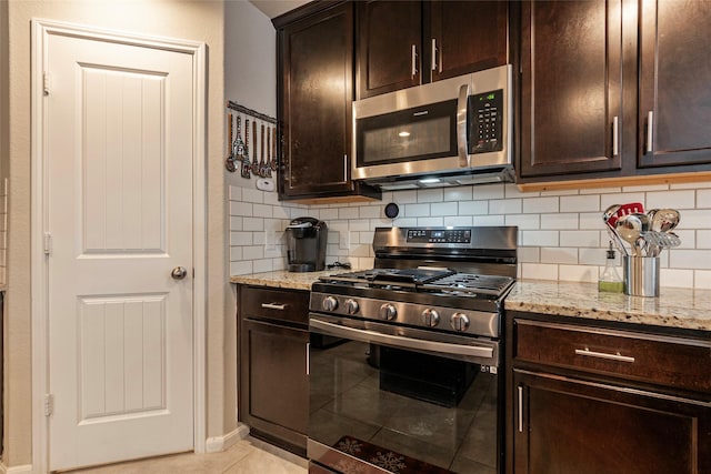 kitchen featuring tasteful backsplash, dark brown cabinetry, stainless steel appliances, and light stone countertops