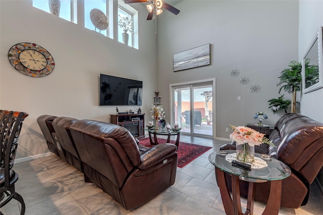 living room featuring light tile patterned floors, ceiling fan, and a high ceiling