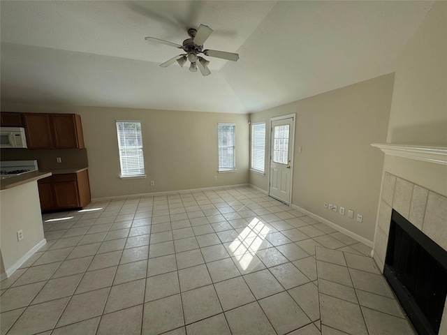 unfurnished living room with ceiling fan, a fireplace, vaulted ceiling, and light tile patterned floors