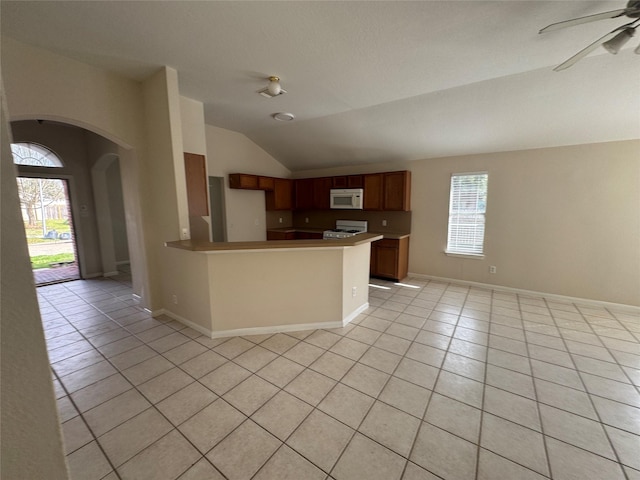 kitchen with lofted ceiling, ceiling fan, range, light tile patterned flooring, and kitchen peninsula