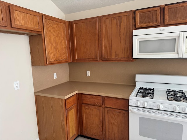 kitchen featuring white appliances, vaulted ceiling, and a textured ceiling