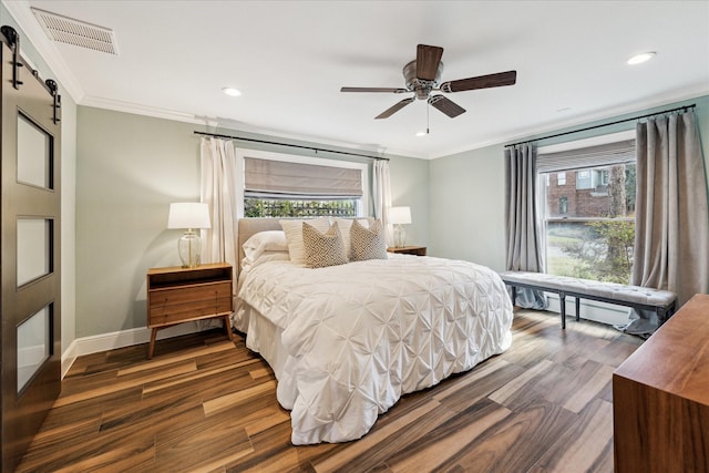 bedroom featuring multiple windows, ornamental molding, and a barn door