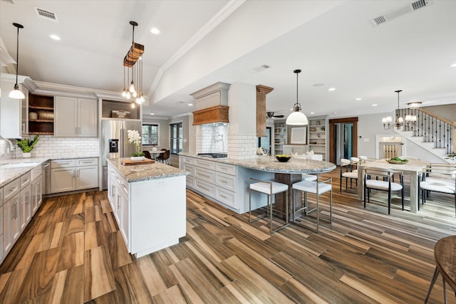 kitchen featuring a center island, hanging light fixtures, a kitchen breakfast bar, kitchen peninsula, and light stone countertops