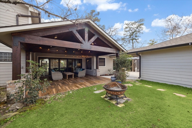 back of house featuring a wooden deck, a lawn, and an outdoor fire pit