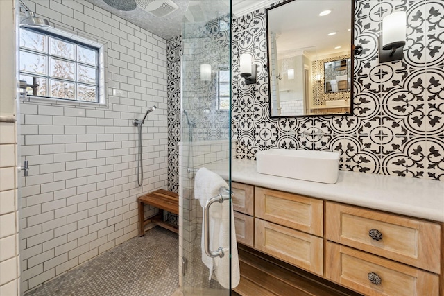 bathroom with tiled shower, vanity, and tile walls