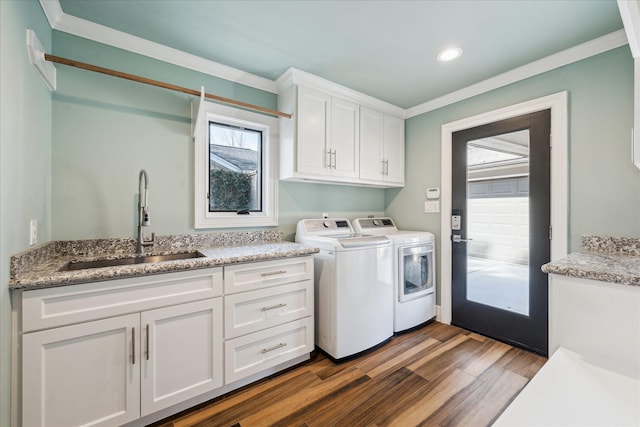 clothes washing area featuring sink, hardwood / wood-style floors, washing machine and dryer, cabinets, and ornamental molding