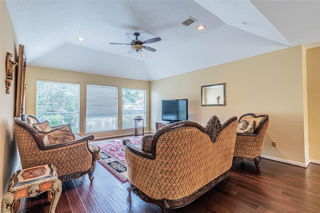 living room featuring dark wood-type flooring, lofted ceiling, a textured ceiling, a tray ceiling, and ceiling fan