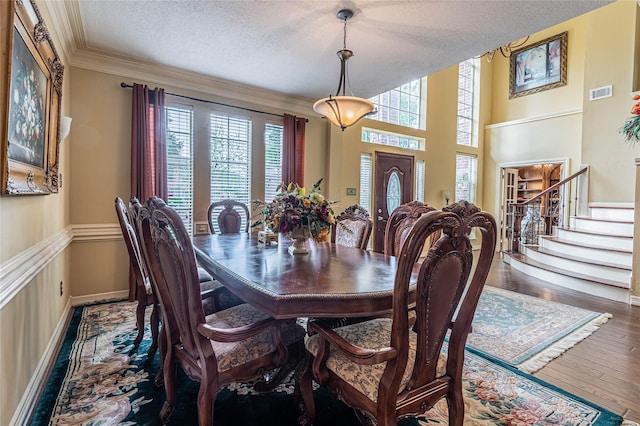 dining area with crown molding, plenty of natural light, wood-type flooring, and a textured ceiling