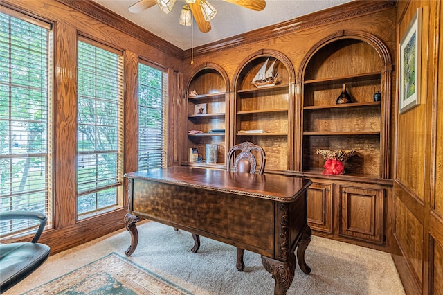 office featuring built in features, wooden walls, ceiling fan, light carpet, and a textured ceiling