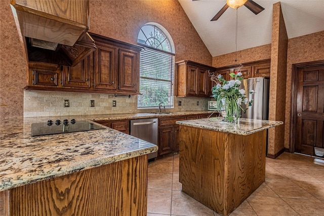 kitchen featuring light tile patterned flooring, a kitchen island, backsplash, stainless steel appliances, and light stone countertops