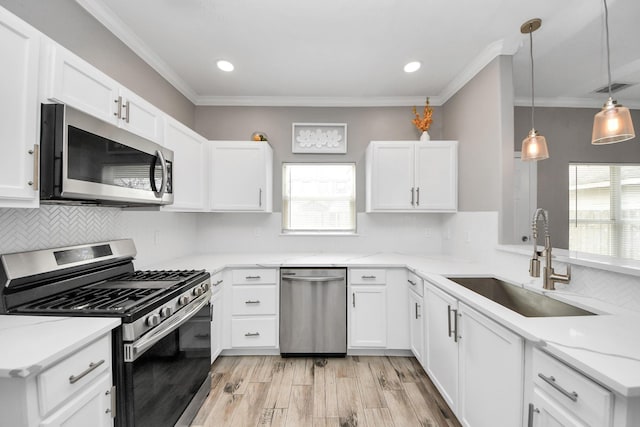 kitchen with sink, white cabinetry, pendant lighting, stainless steel appliances, and light stone countertops