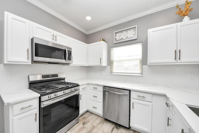 kitchen featuring stainless steel appliances, white cabinetry, and crown molding