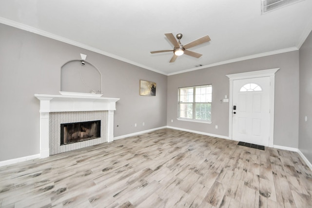 unfurnished living room with crown molding, a tiled fireplace, and light wood-type flooring