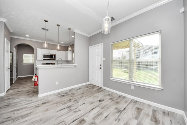 kitchen featuring pendant lighting, white cabinets, light wood-type flooring, and kitchen peninsula