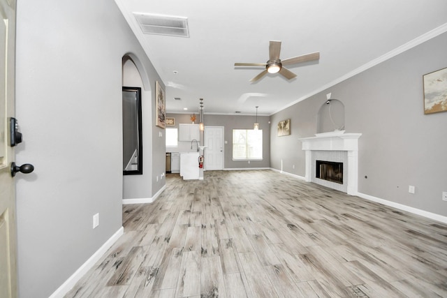 unfurnished living room featuring sink, crown molding, light hardwood / wood-style floors, and ceiling fan