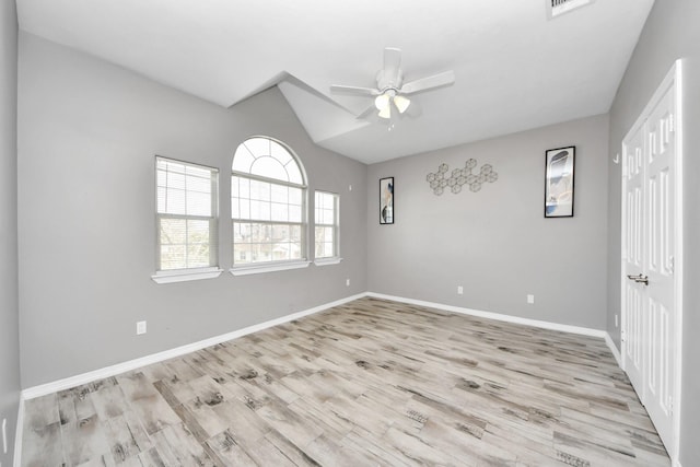 empty room with vaulted ceiling, ceiling fan, and light wood-type flooring