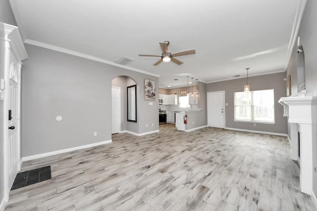 unfurnished living room featuring sink, crown molding, ceiling fan, and light wood-type flooring