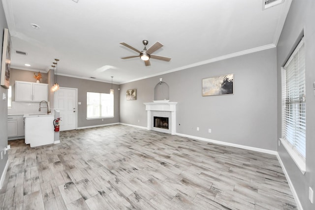 unfurnished living room with light hardwood / wood-style flooring, ornamental molding, and ceiling fan