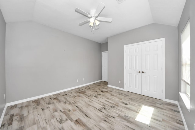 unfurnished bedroom featuring vaulted ceiling, a closet, ceiling fan, and light wood-type flooring