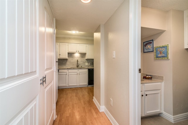 corridor with sink, a textured ceiling, and light hardwood / wood-style floors